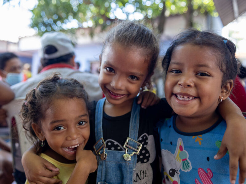 Three young girls hugging and smiling