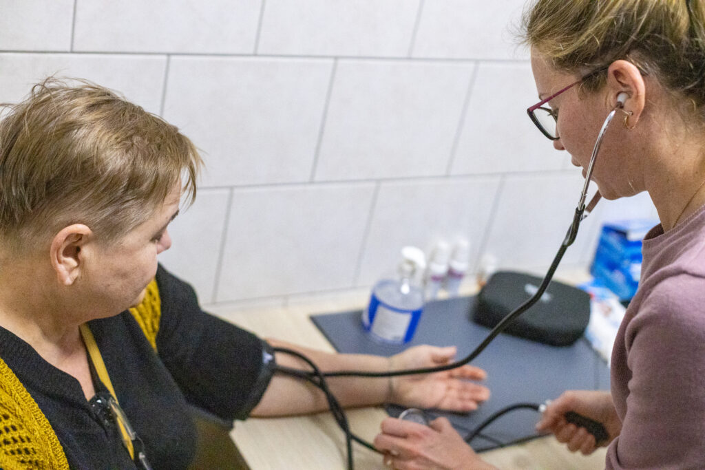 Maryna takes the blood pressure of a Ukrainian refugee at the accommodation center