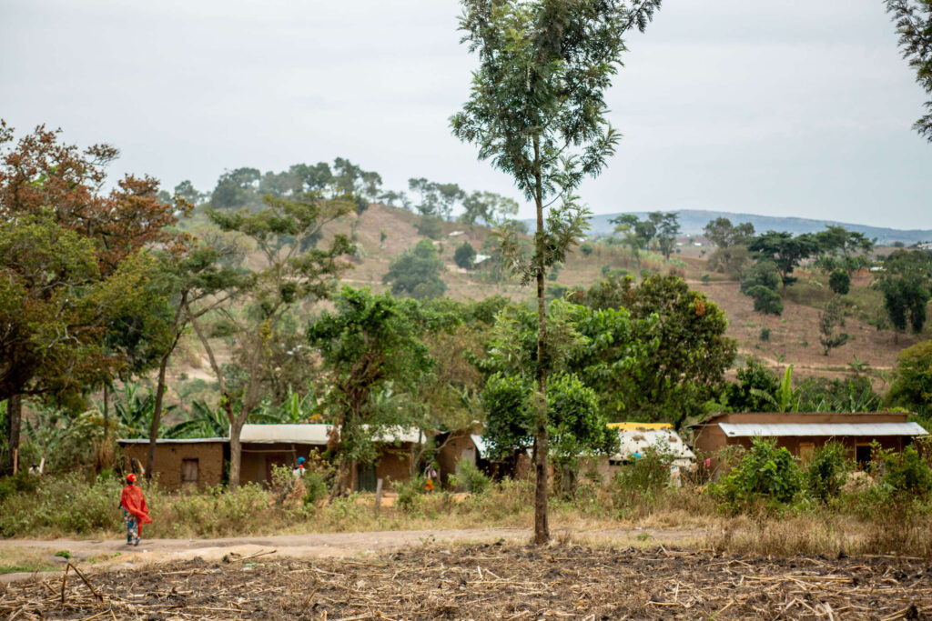 Houses made from mud sit in front of a hill in Rwamwanja Refugee Settlement.